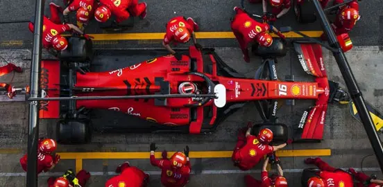 Ferrari Formula 1 car in the pit stop with team members performing a tire change during a race, showcasing teamwork and precision in motorsport.